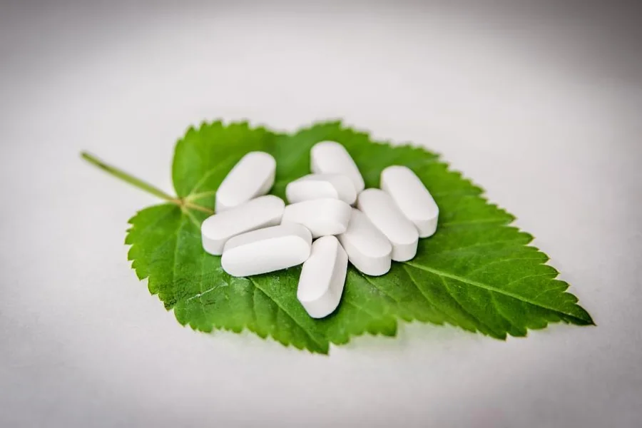 White tablets resting on a green leaf